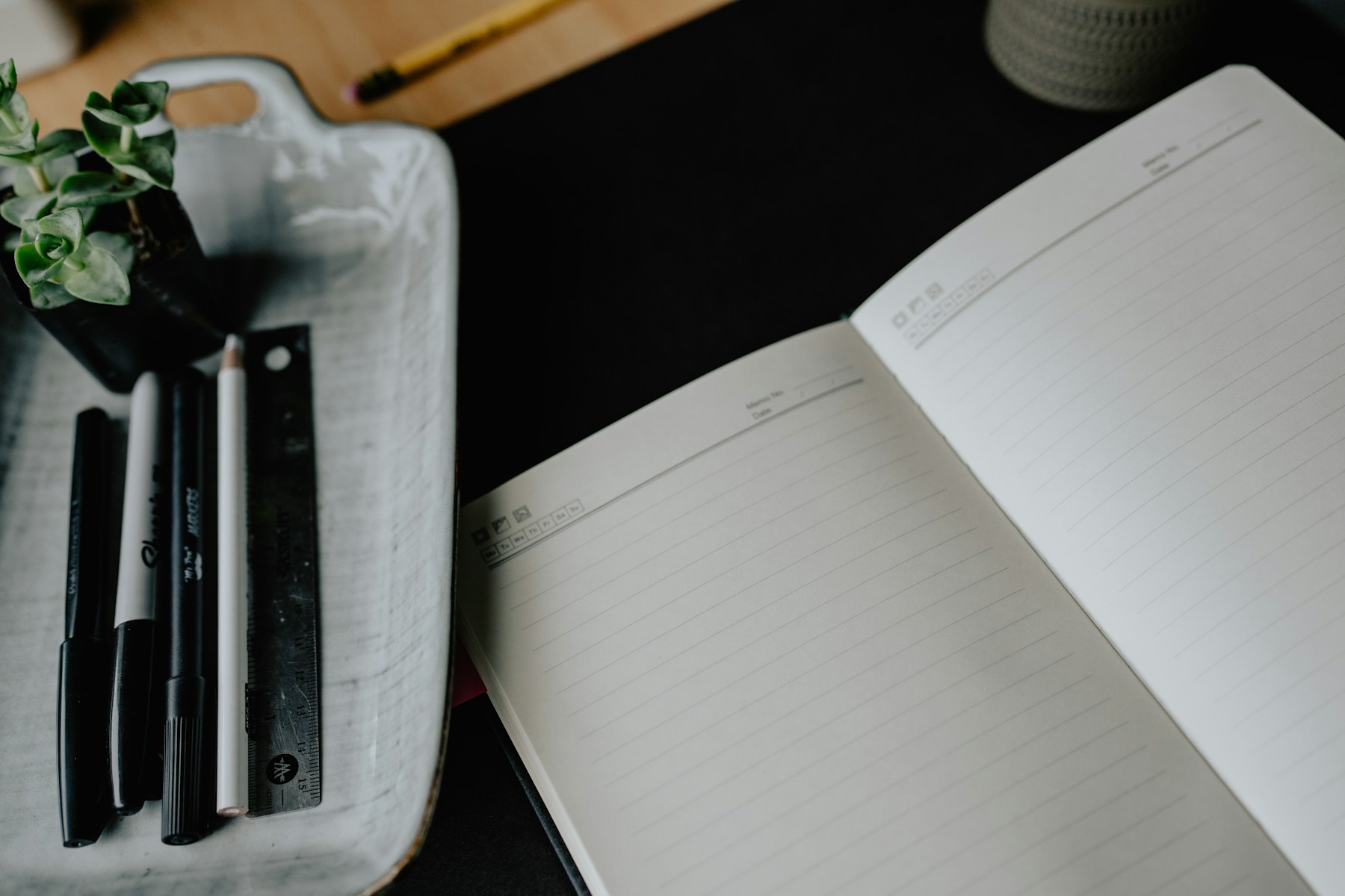 An open lined notebook with pens on a desk